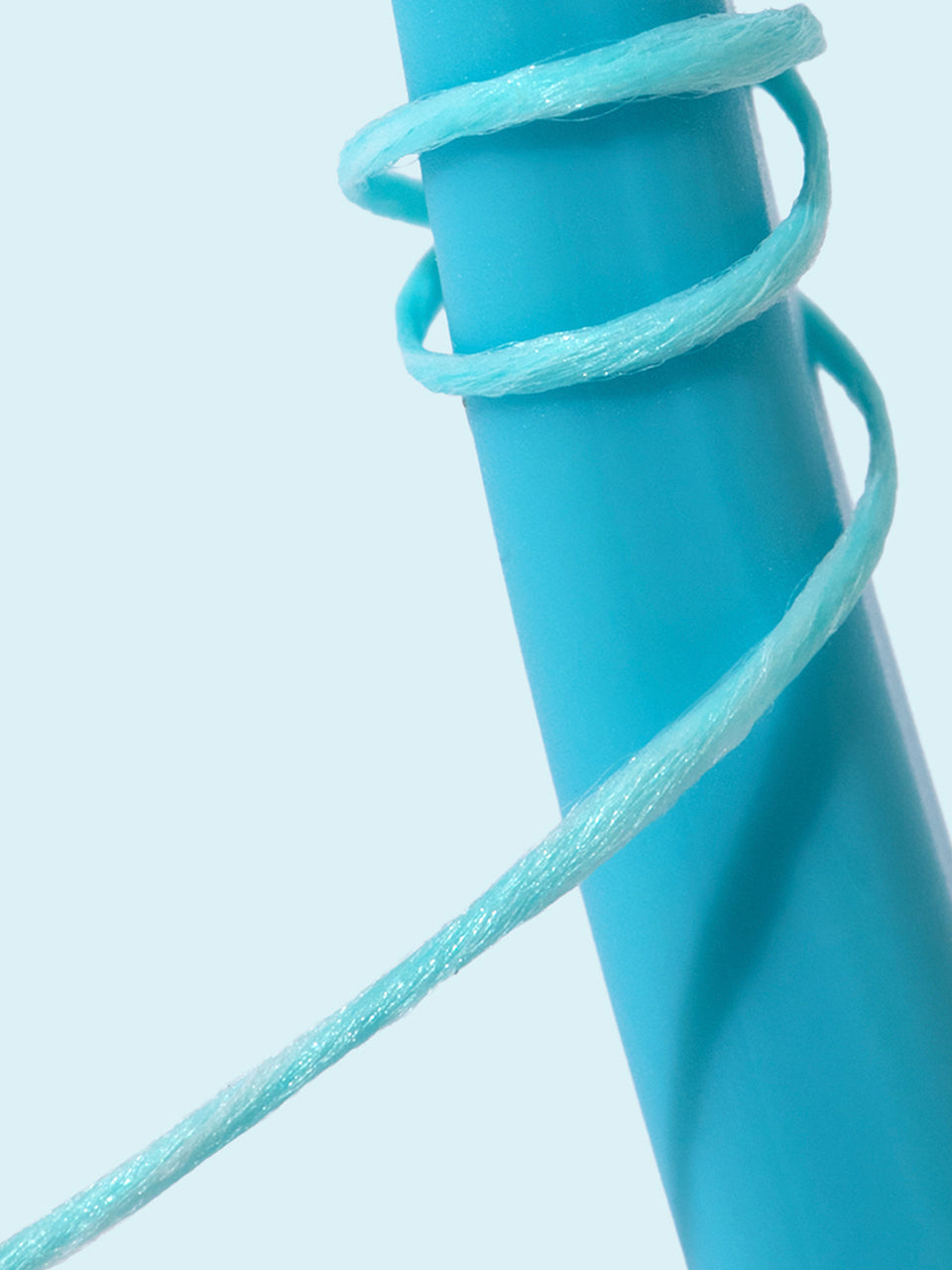 Close-up of a blue floss spool on a light gray background