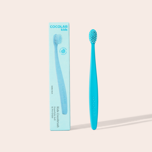 Blue toothbrush with packaging labeled 'Cocolab Kids' on a beige background