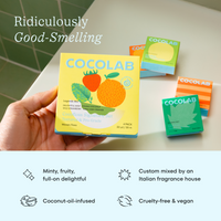 Cocolab product packaging held by a hand with additional packaging in the background on a tiled surface.