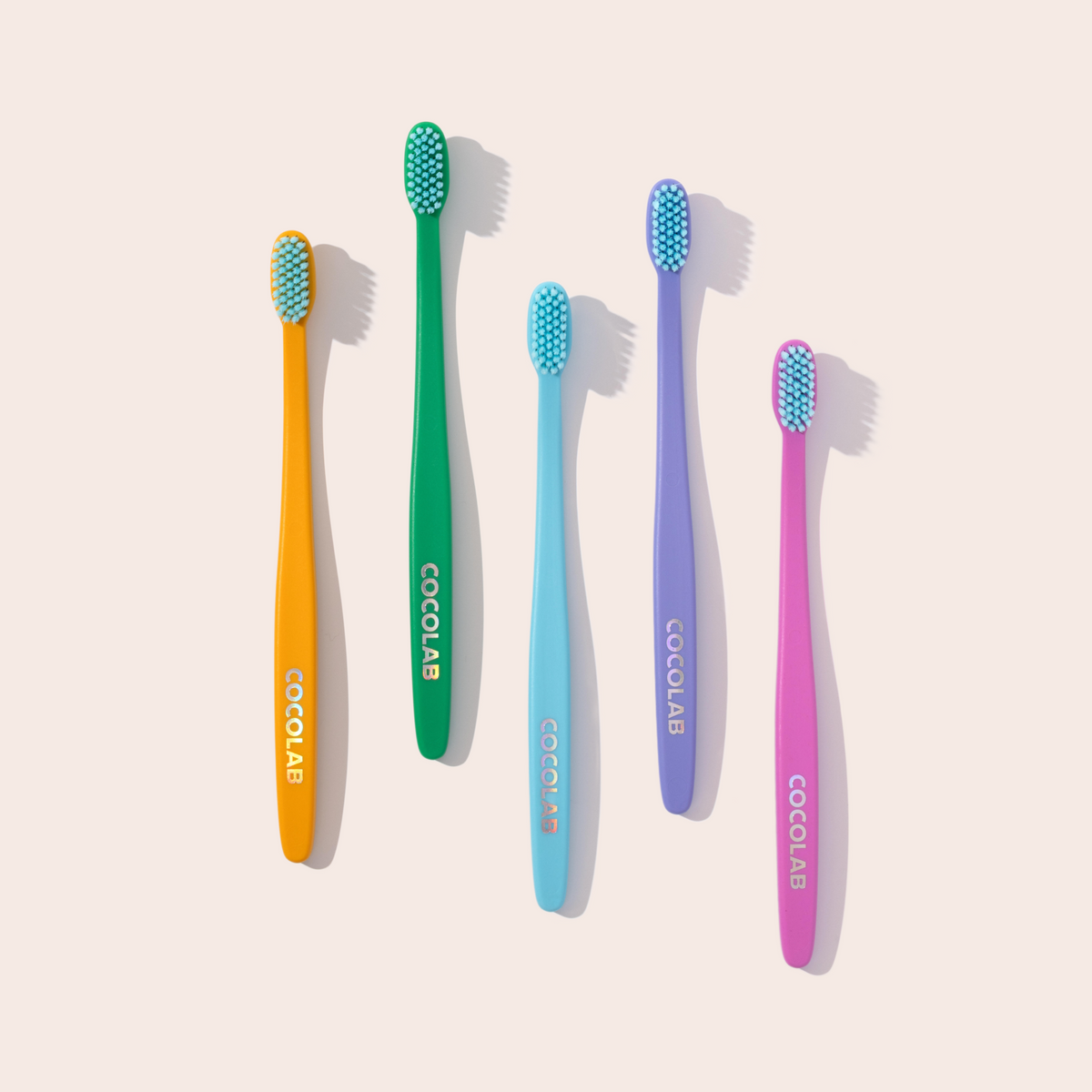 Set of five colorful toothbrushes with 'Cocolab' branding on a light beige background
