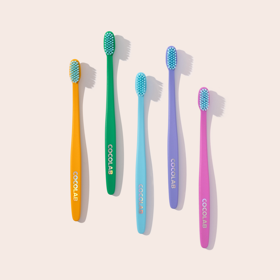 Set of five colorful toothbrushes with 'Cocolab' branding on a light beige background