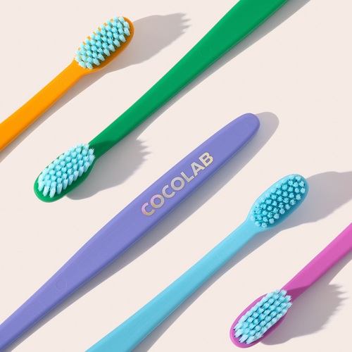 Colorful toothbrushes with 'COCOLAB' branding on a light background