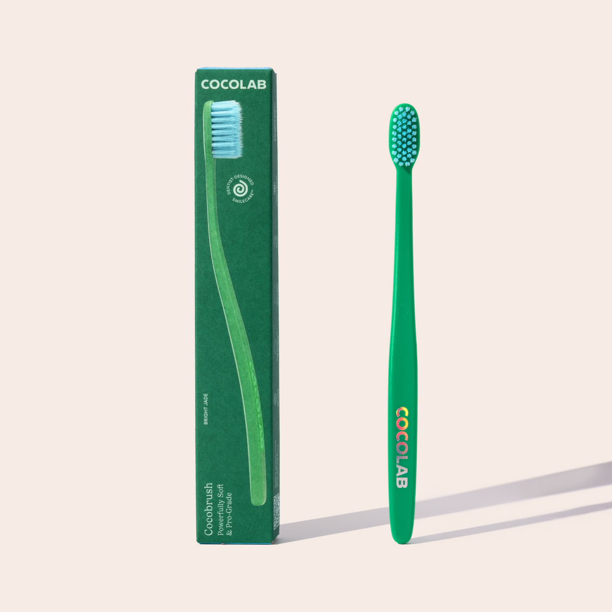 Green toothbrush with Cocolab branding next to its packaging on a light beige background