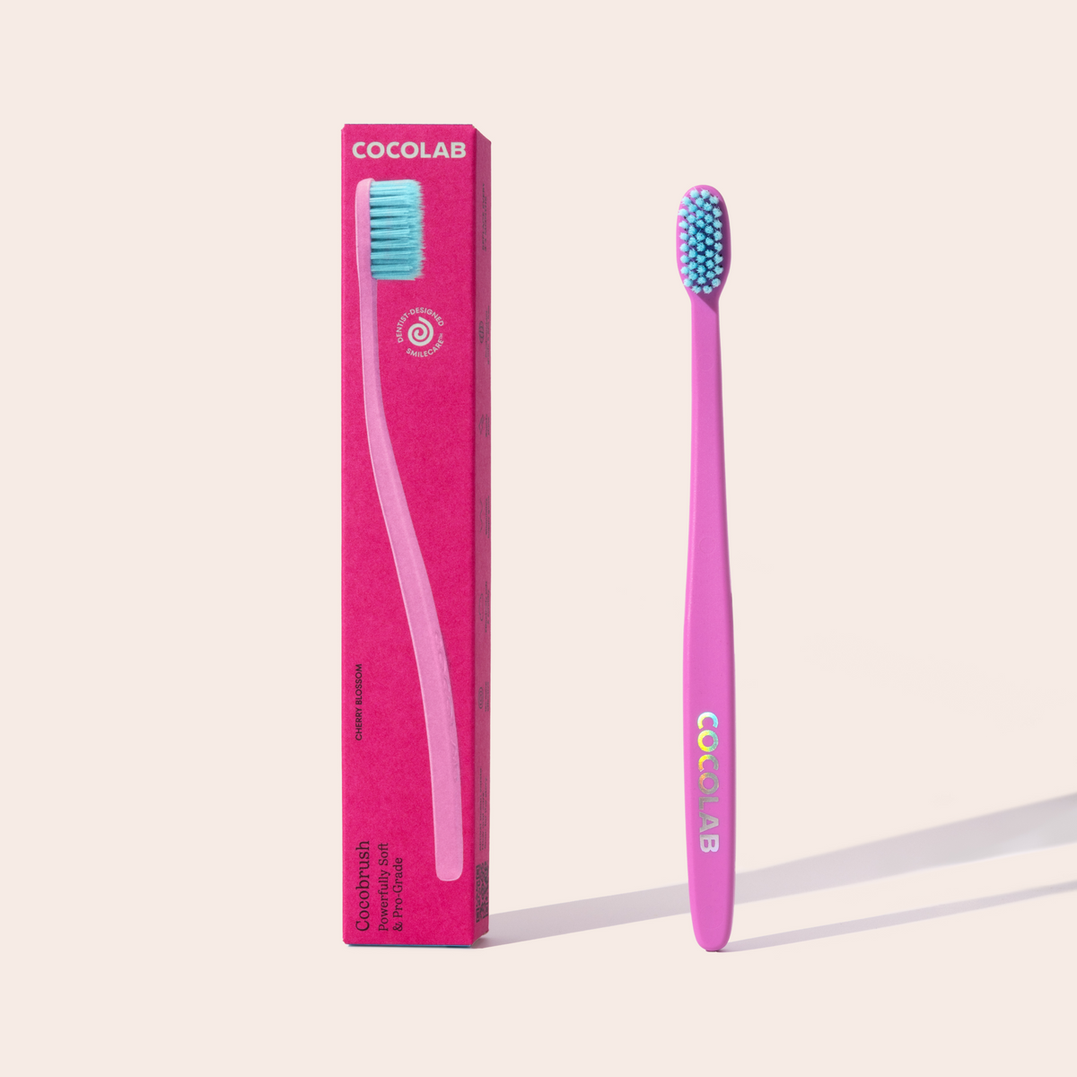 Pink toothbrush with blue bristles and Cocolab packaging on a light pink background