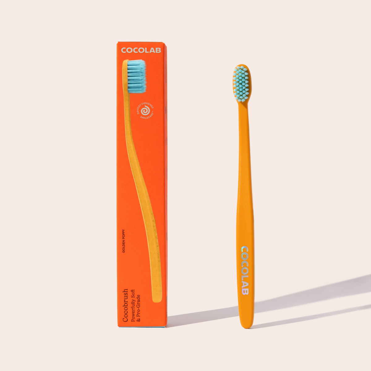 Orange toothbrush with blue bristles and packaging labeled 'Cocolab' on a light beige background
