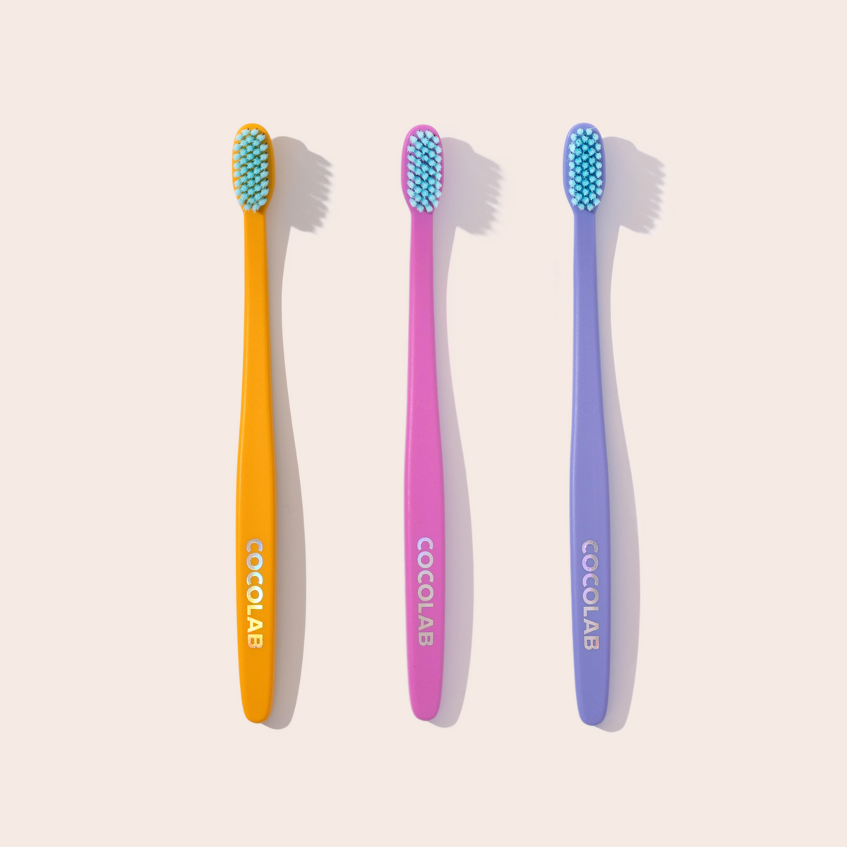 Three colorful toothbrushes with 'COCOLAB' branding on a light background