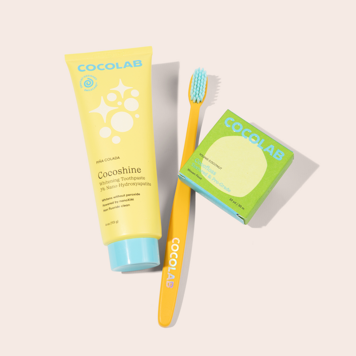 Cocoshine toothpaste, toothbrush, and cocofloss on a light gray background
