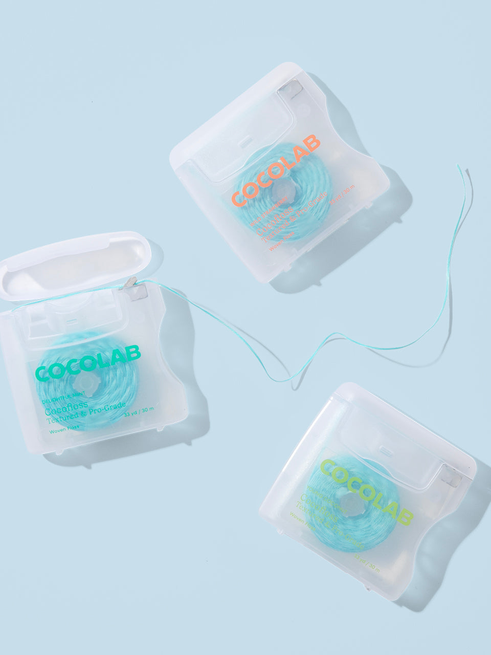 Three containers of dental floss with 'Cocolab' branding on a light blue background