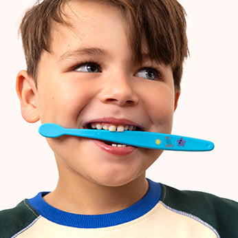 Child holding a blue toothbrush with a cartoon character on a white background